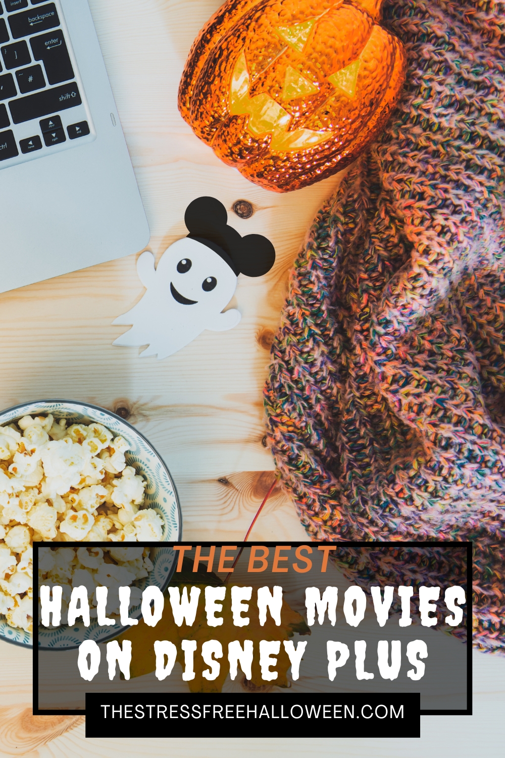 desk with laptop, popcorn, blanket, pumpkin, and a little ghost wearing a mickey hat with text the best Halloween movies on disney plus