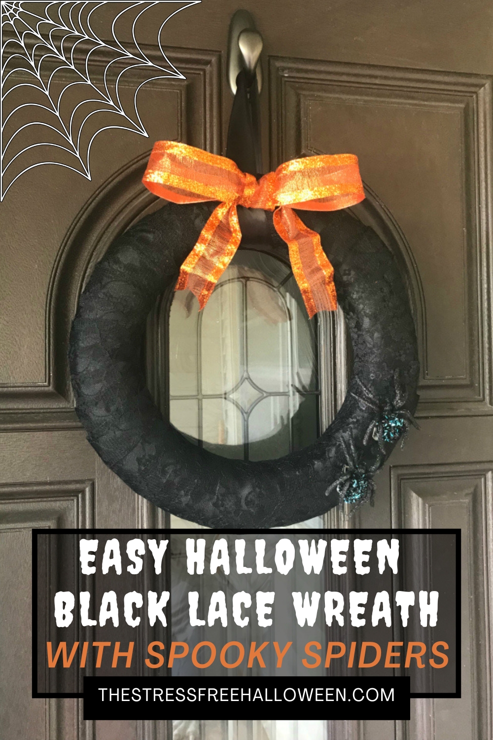 black lace halloween wreath with orange ribbon on top and spooky spiders on the bottom hanging on brown front door.
